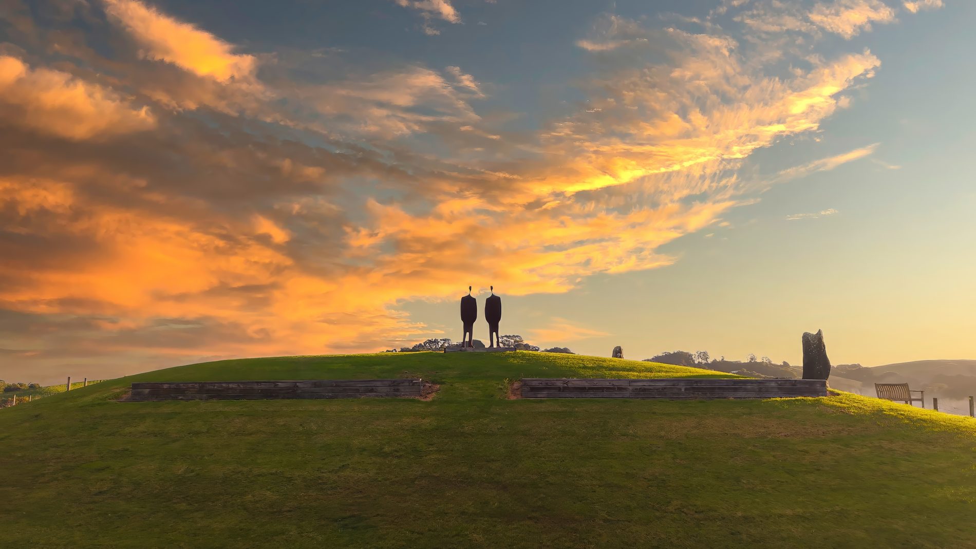 Sculpture figures silhouetted on the rise above the Oak Hill Vineyard at sunset